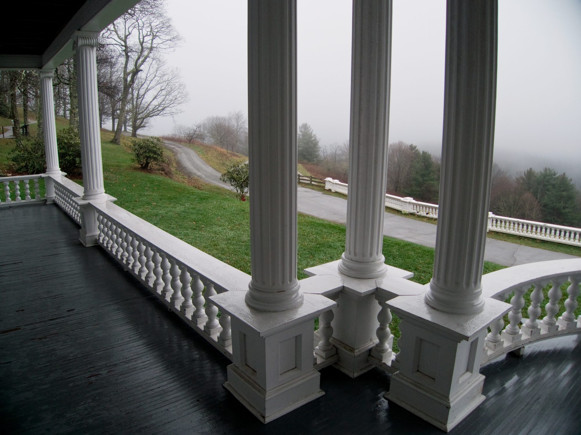 Columns along a porch rail, a road below in mist